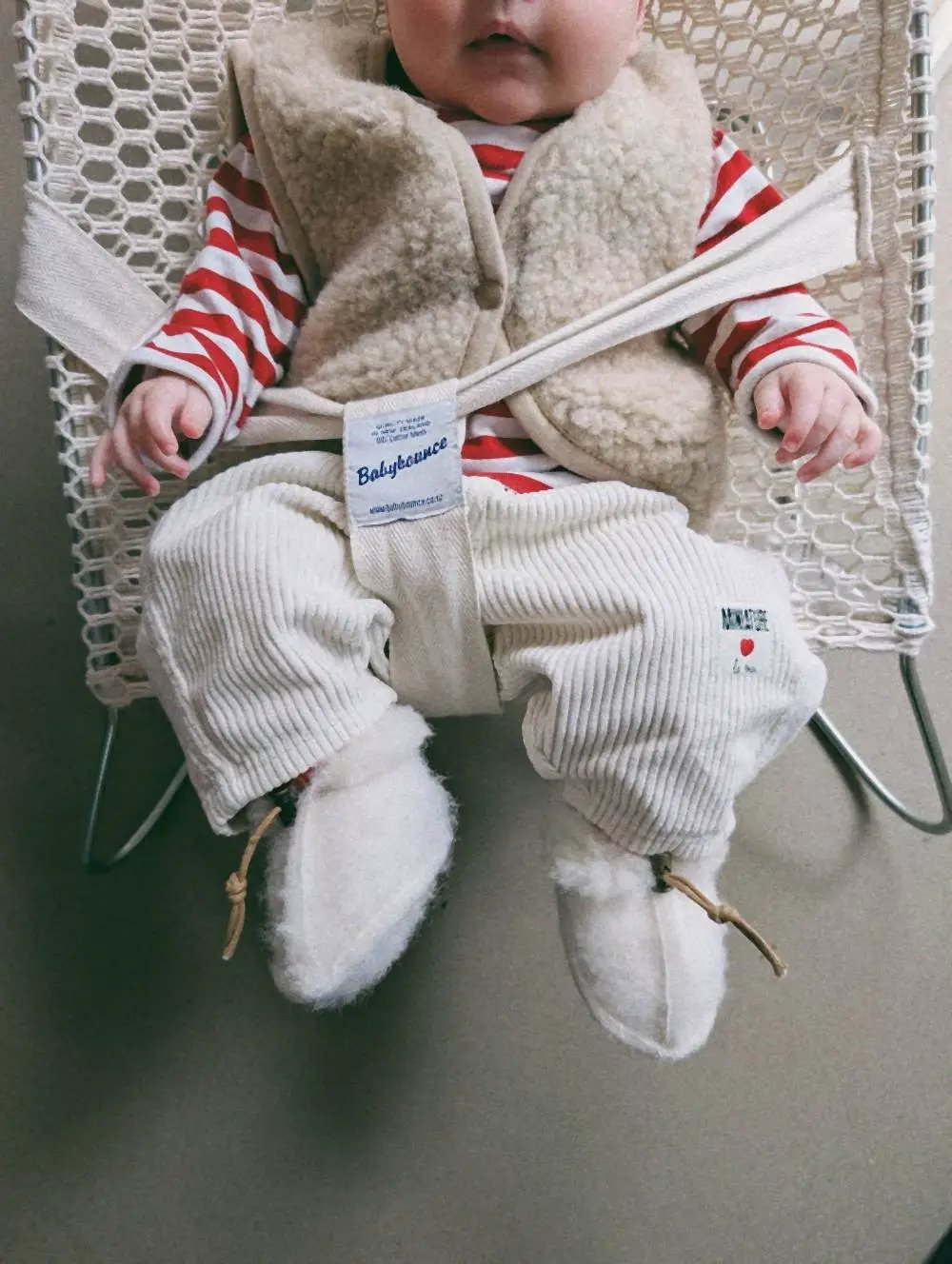 ALWERO gilet en laine pour bébé tan, sherpa beige, porté par bébé en pull à rayures rouges et blanches