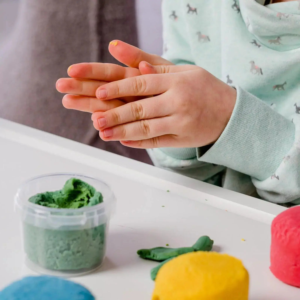 NEOGRÜN pâte à modeler végan bio Loki avec pot vert et boules bleues et jaunes sur table