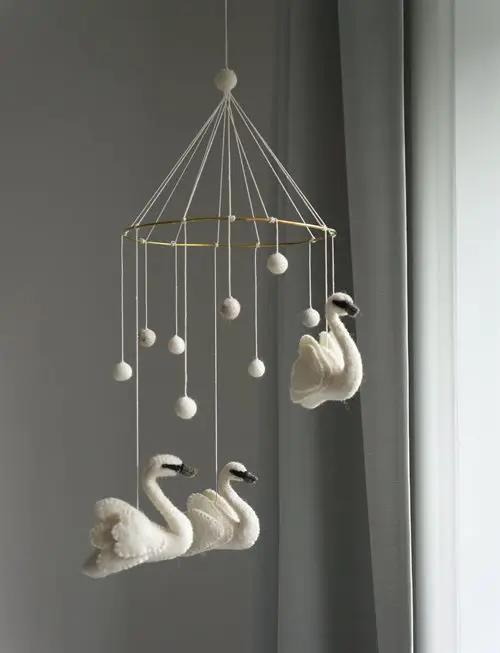 GAMCHA baby mobile with three white felt swans and hanging pom-poms