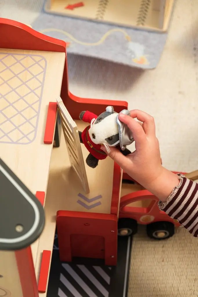 Caserne des pompiers en bois EGMONT TOYS avec camion rouge et main tenant une petite peluche animale