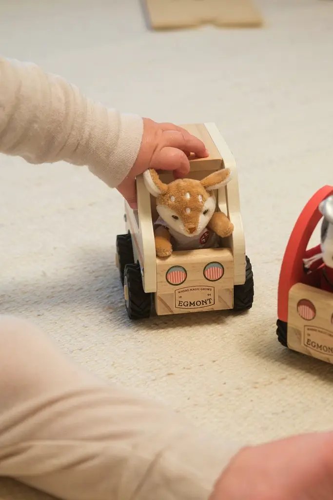 Wooden ambulance toy by Citron Grenadine (EGMONT) with plush deer driver; two wooden trucks shown.