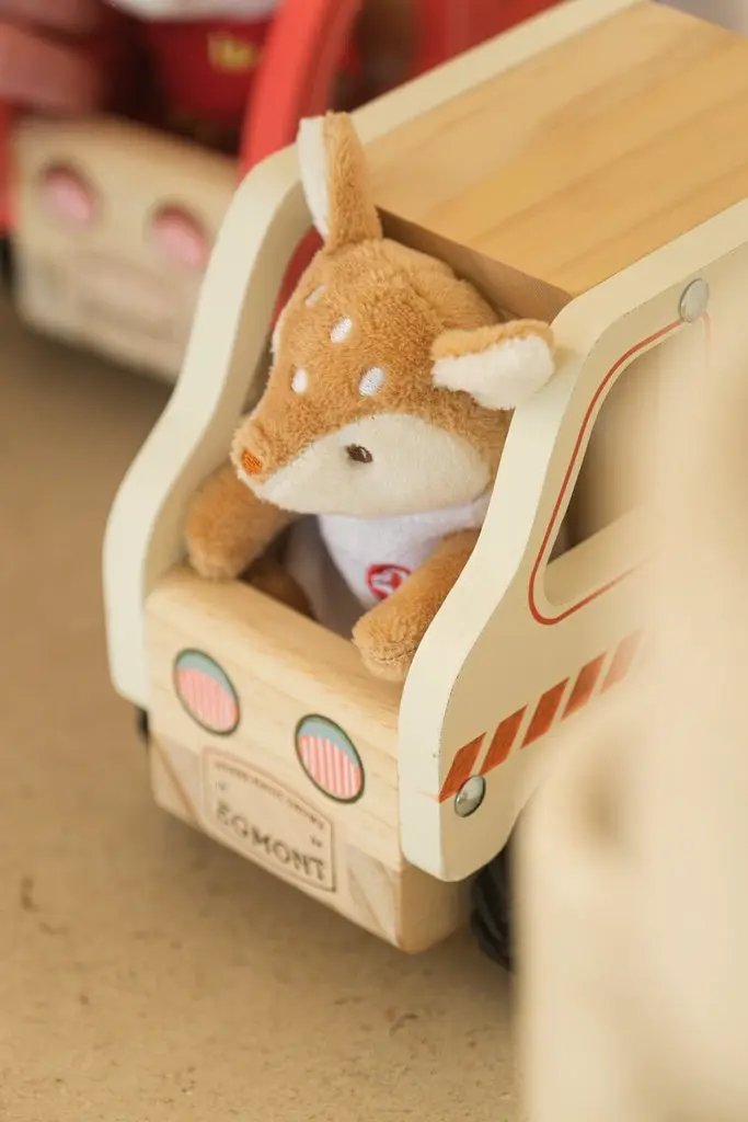 Egmont Toys wooden ambulance toy with cream sides and orange stripes, plush deer inside