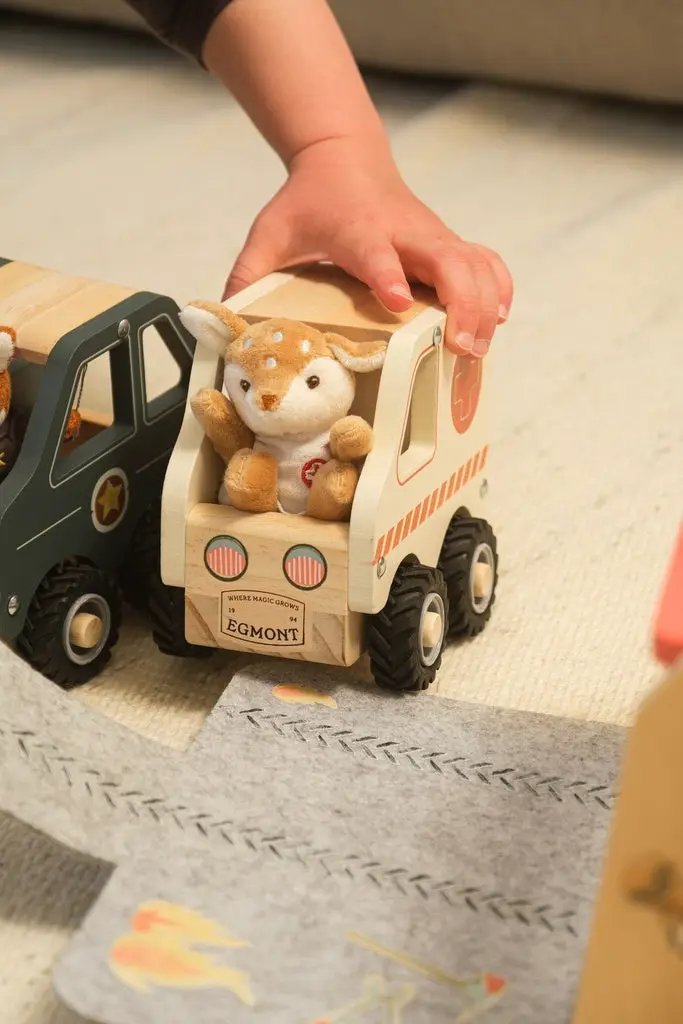 Egmont Toys wooden ambulance toy with plush deer passenger; child hand on top