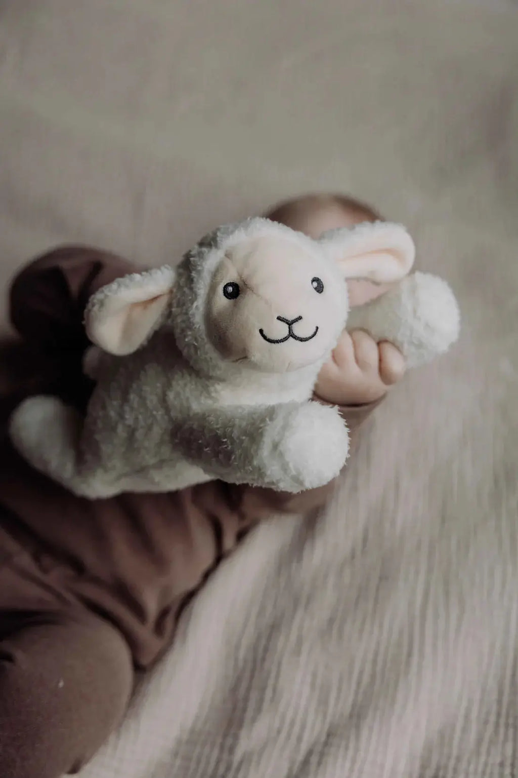 Rosie plush sheep doudou from Flow Amsterdam, soft white stuffed toy held by a baby