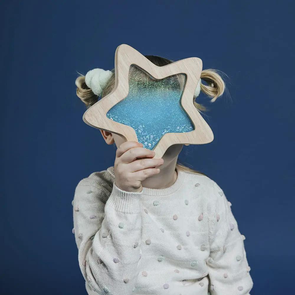 PETIT BOUM étoile sensorielle orionis blue rattle in a wooden star frame with glittery blue glaze