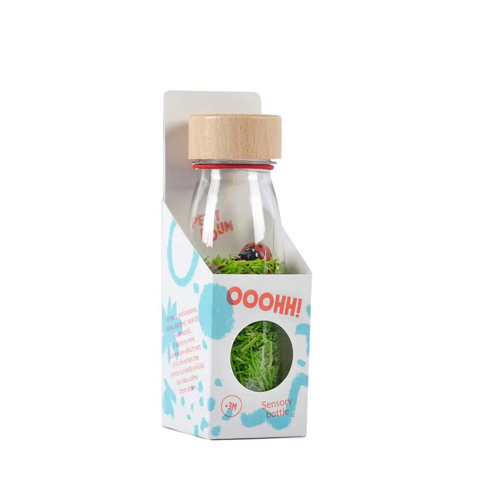 Bouteille sensorielle Petit Boum par Citron Grenadine, bouchon bois, coccinelle, emballage blanc à motifs bleus.
