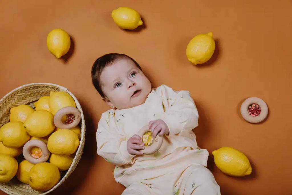PETIT BOUM donut sensoriel, jouet de dentition citron jaune avec décor citrons et bébé tenant l'anneau