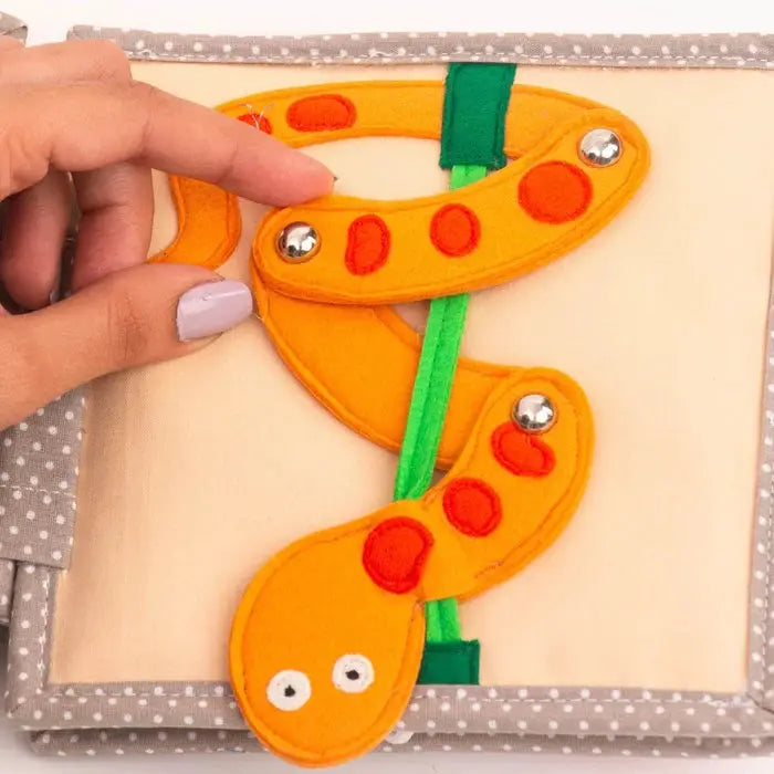 JOLLY DESIGNS livre d'éveil pour bébé 6m+ Citron Grenadine; chenille en feutre orange sur page beige, ruban vert