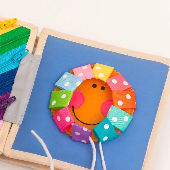 JOLLY DESIGNS livre d'éveil / magic bird 12m+, fabric baby book with a smiling sun and rainbow ring on blue page