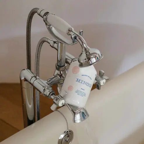 MINOIS mousse de bain bubble bath by Citron Grenadine on chrome bathtub faucet; white bottle with pink dots