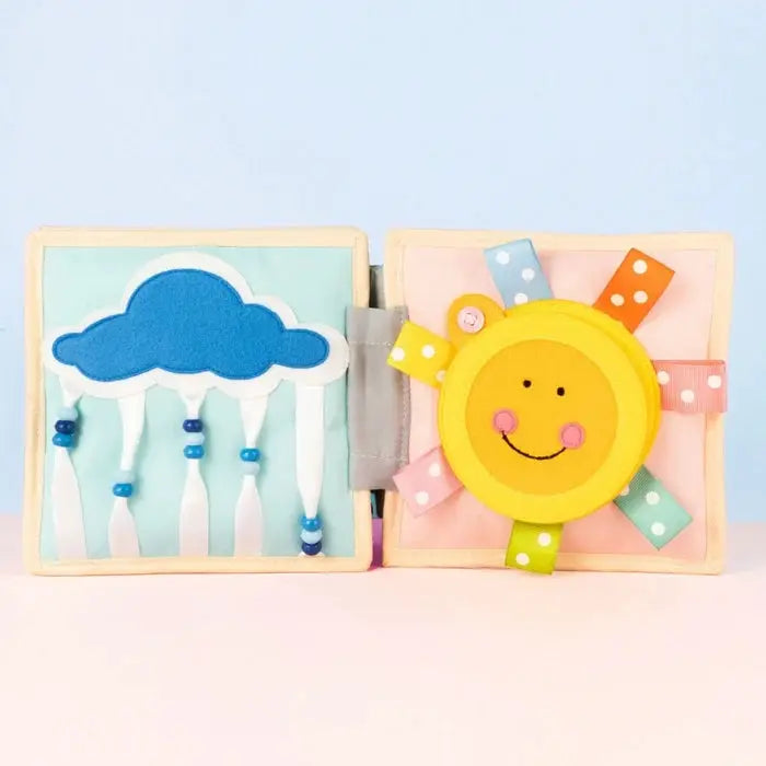 JOLLY DESIGNS livre d'éveil bébé par Citron Grenadine, pages en tissu avec soleil souriant et nuage bleu