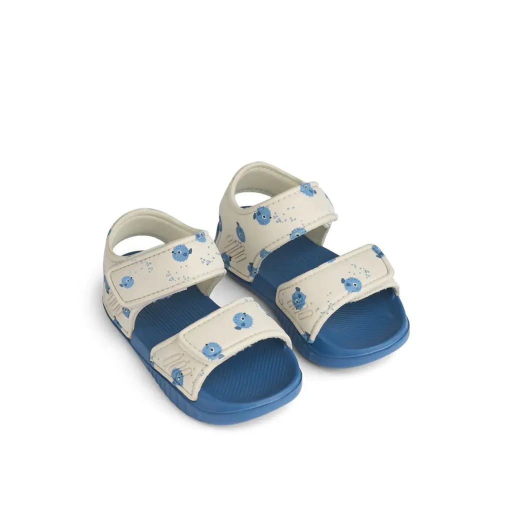 Two LIEWOOD baby sandals with cream straps featuring blue pufferfish print and blue soles