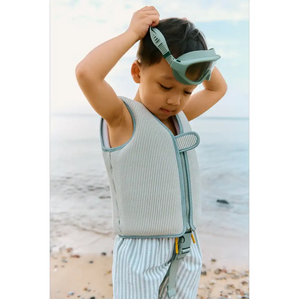 LIEWOOD dove swim vest for kids in peppermint sandy; striped light-blue fabric with front zipper on the beach.