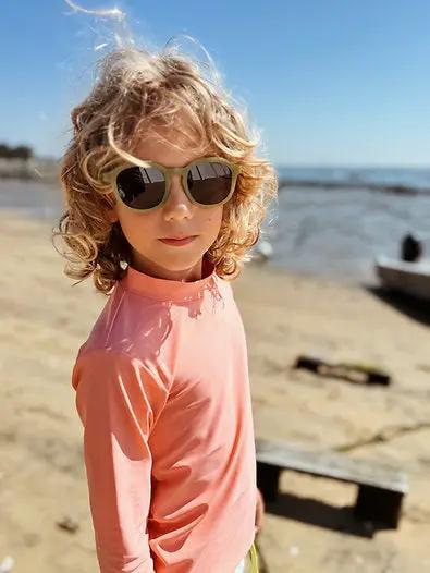 BAÏNES papaya UV-protective peach one-piece swimsuit on a child at the beach