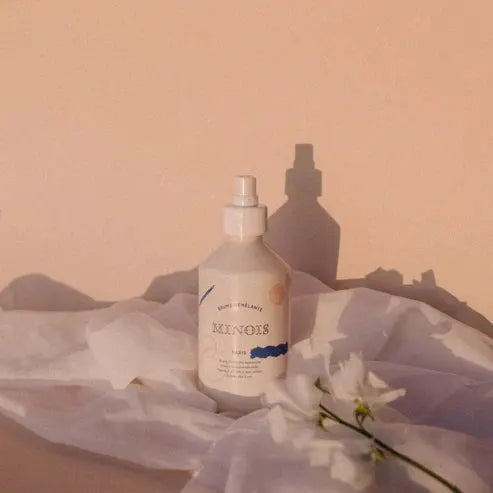 MINOIS brume démêlante spray by Citron Grenadine, white plastic bottle with nozzle on white fabric.