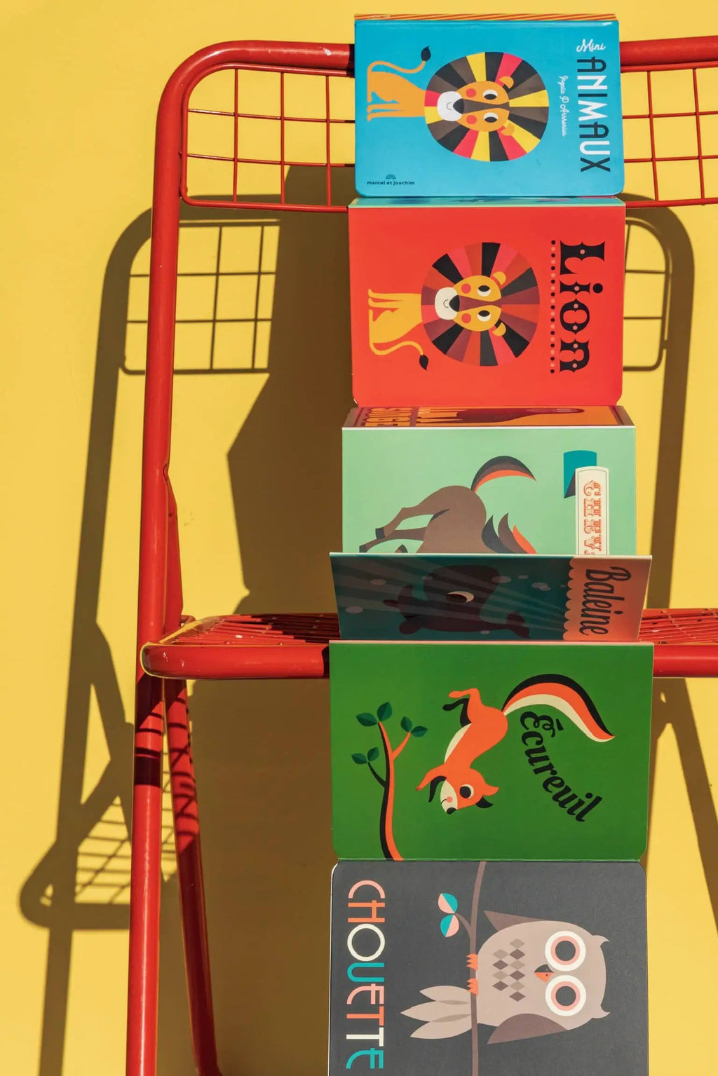 MARCEL ET JOACHIM leporello animaux, five colorful Citron Grenadine print books stacked on a red shelf