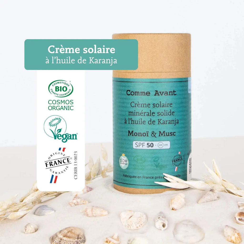 Crème solaire minérale solide COMME AVANT SPF50 à l’huile de karanja, tube turquoise sur fond sable