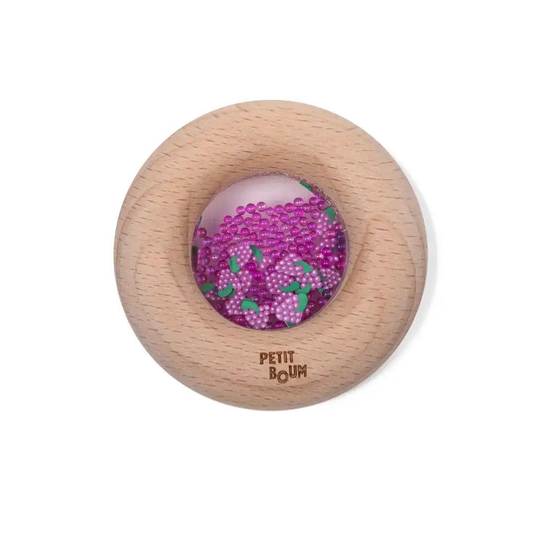 Petit Boum sensory donut teether in natural wood with pink grape beads and green leaf accents