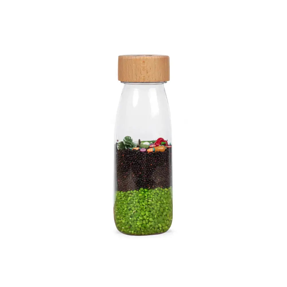 Petit Boum sensory bottle veggies by Citron Grenadine, glass bottle with wood cap, green seeds and brown beads.